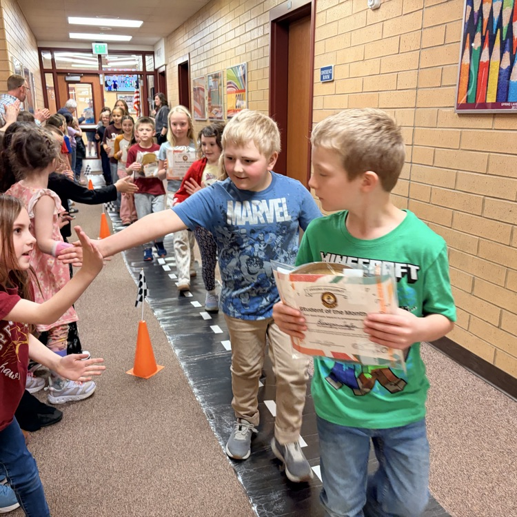 students of the month in a line while other kids cheer them on