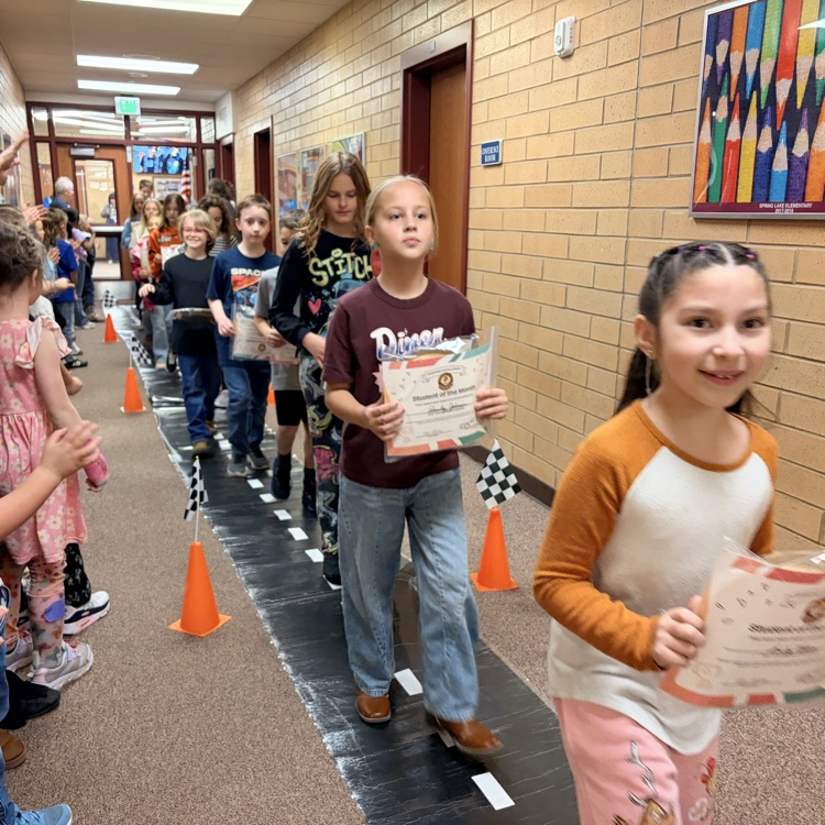 students of the month in a line while other kids cheer them on