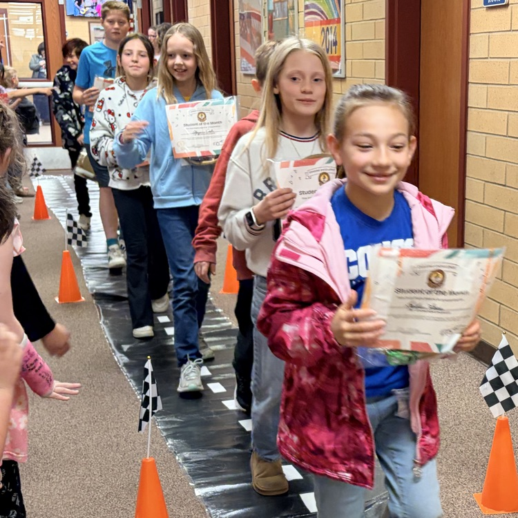 students of the month in a line while other kids cheer them on