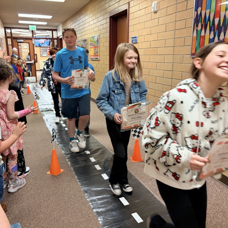 students of the month in a line while other kids cheer them on