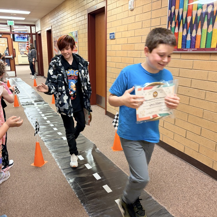 students of the month in a line while other kids cheer them on