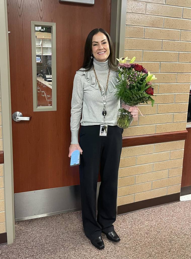 Mrs. Steiner at school holding flowers.