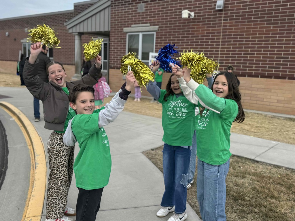 A group of students holding pom poms welcoming students to school.