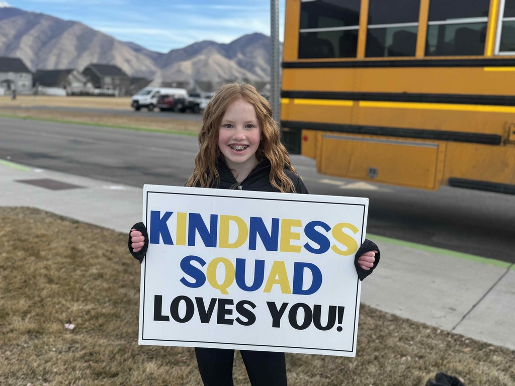 Student holding a sign that says: Kindness Squad Loves You!