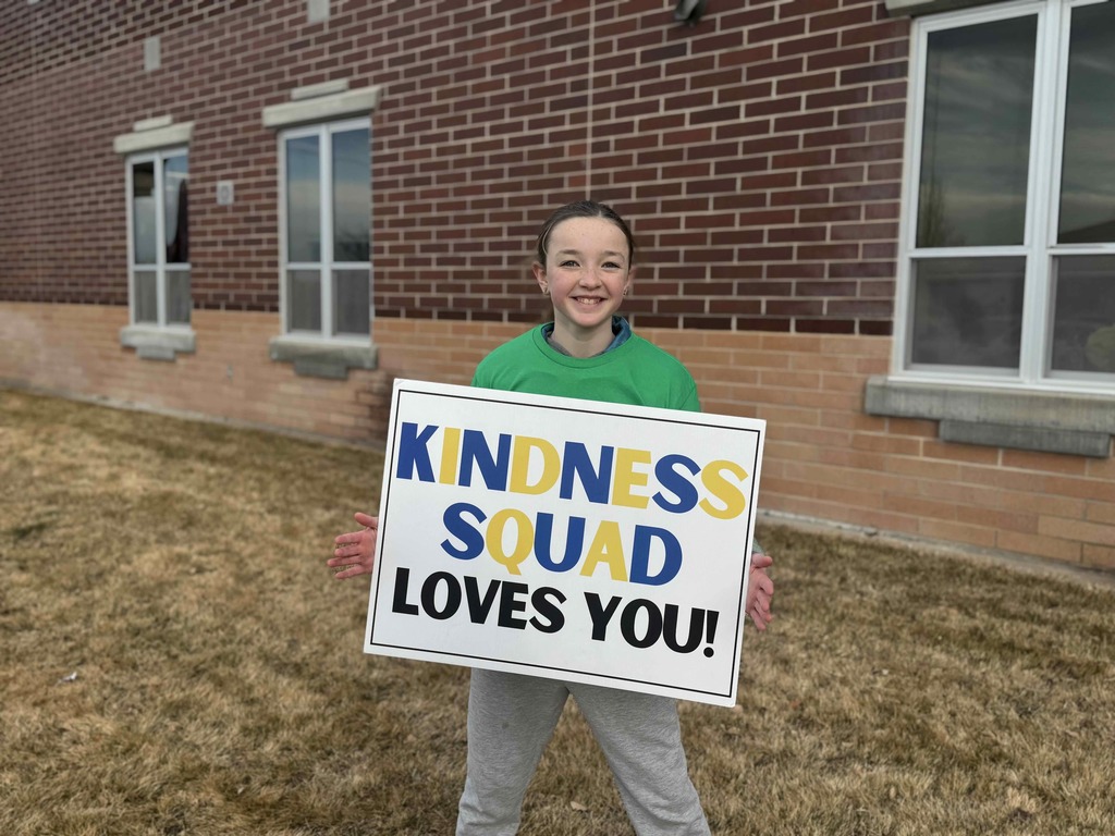 Student holding a sign that says: Kindness Squad Loves You!