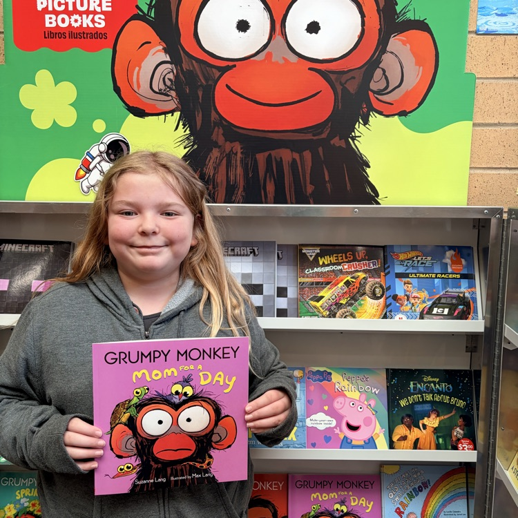 a third grade girl holding a grumpy monkey book in front of a grumpy monkey poster 