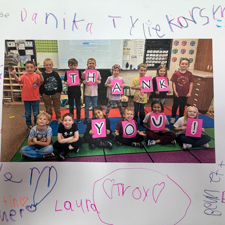 a first grade class holding up the letters to spell out “thank you.” 