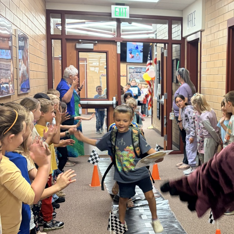 first grade students cheering on their classmates walking through the hall 