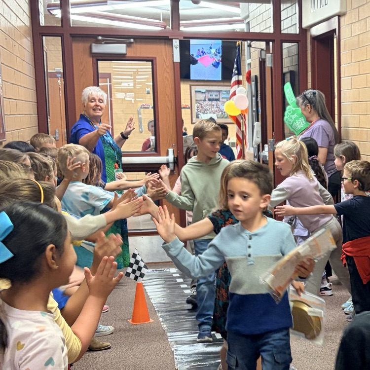 first grade students cheering on their classmates walking through the hall 