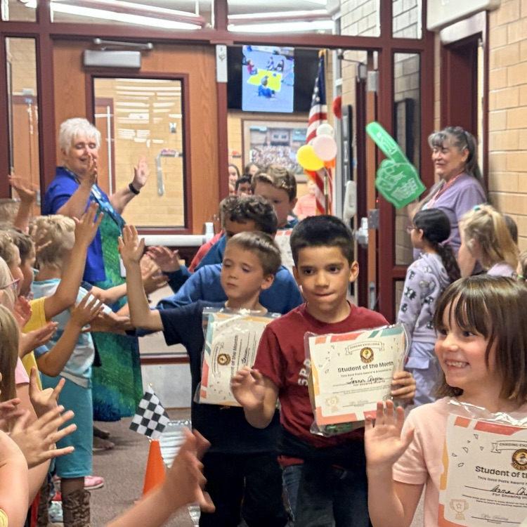 first grade students cheering on their classmates walking through the hall 