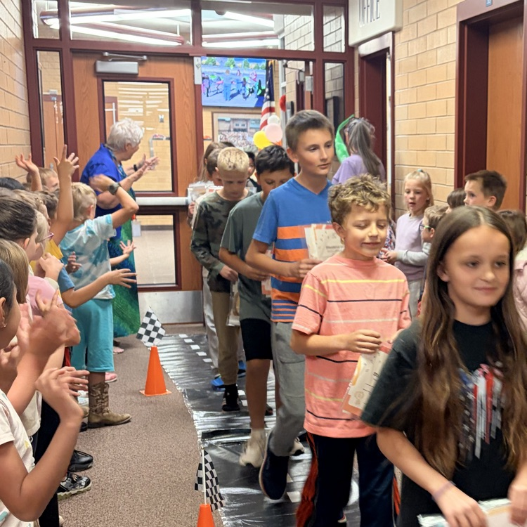 first grade students cheering on their classmates walking through the hall 