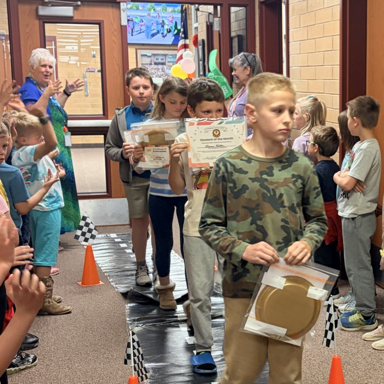first grade students cheering on their classmates walking through the hall 