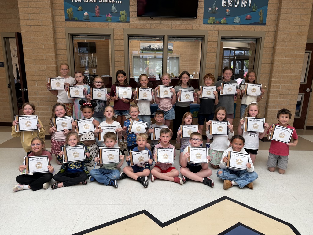 Students in the foyer holding their student of the month certificates.