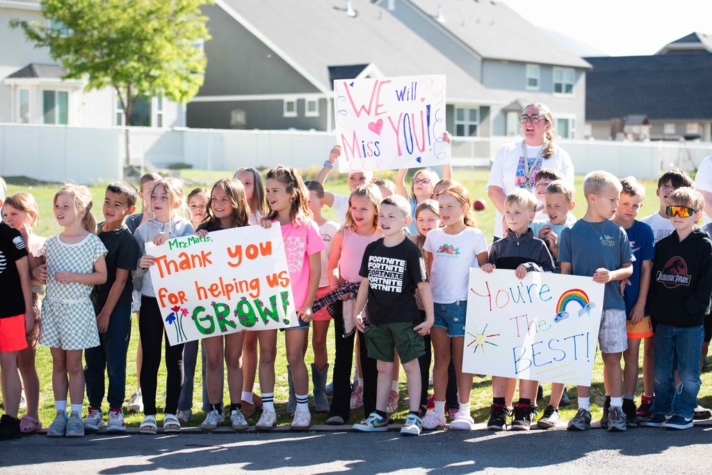 Students holding up signs waiting for Mrs. Matis to arrive.