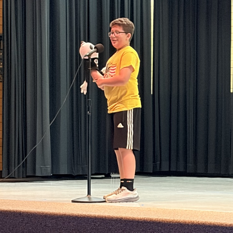 a student holding a puppet in front of a microphone