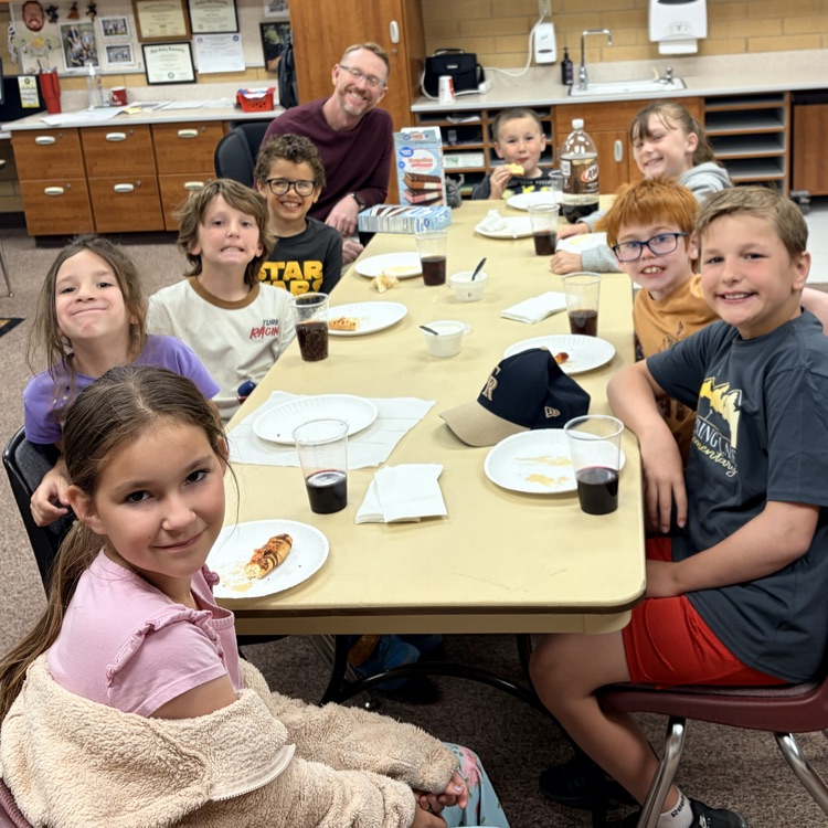 a group of students sitting around a table with Mr. Gowans