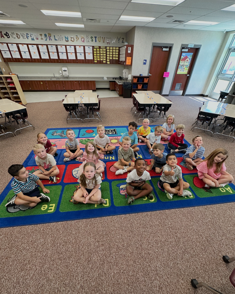 picture of students in kindergarten smiling on a rug