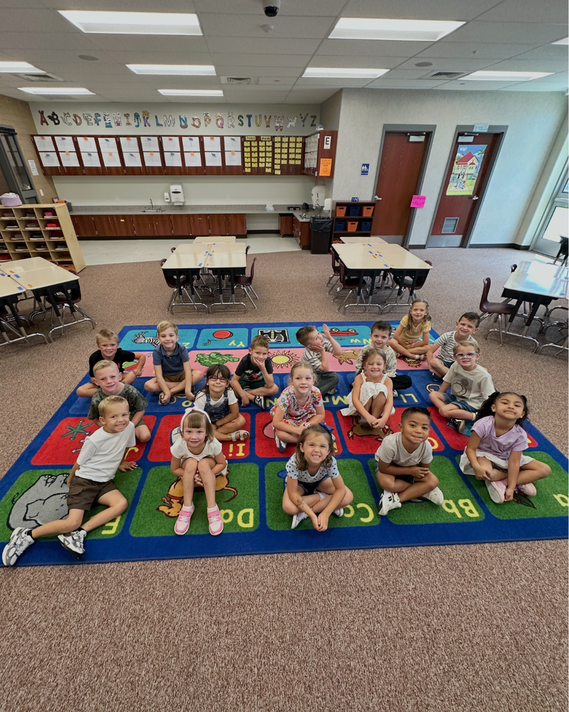 picture of students in kindergarten smiling on a rug