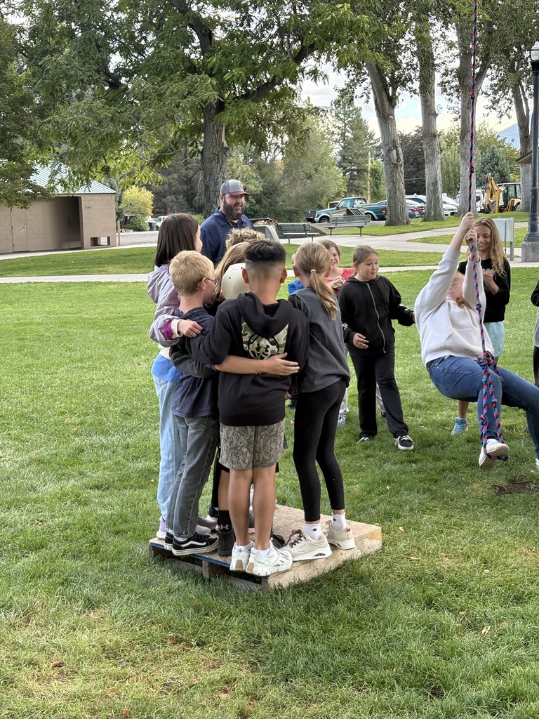 Fifth graders swinging from a rope swing onto a platform