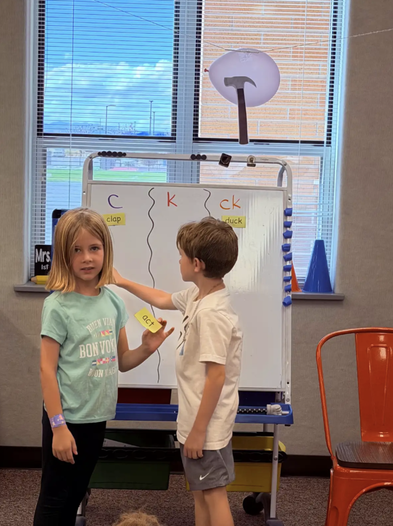 students working at the whiteboard together working on letters and words 