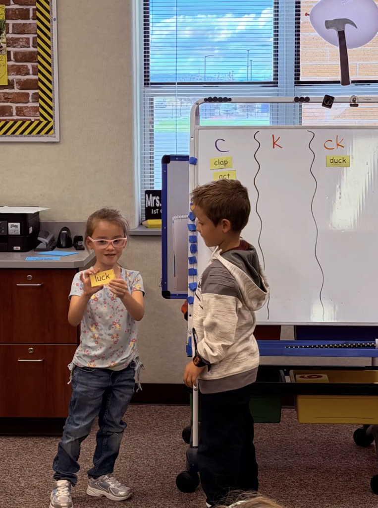 students working at the whiteboard together working on letters and words 