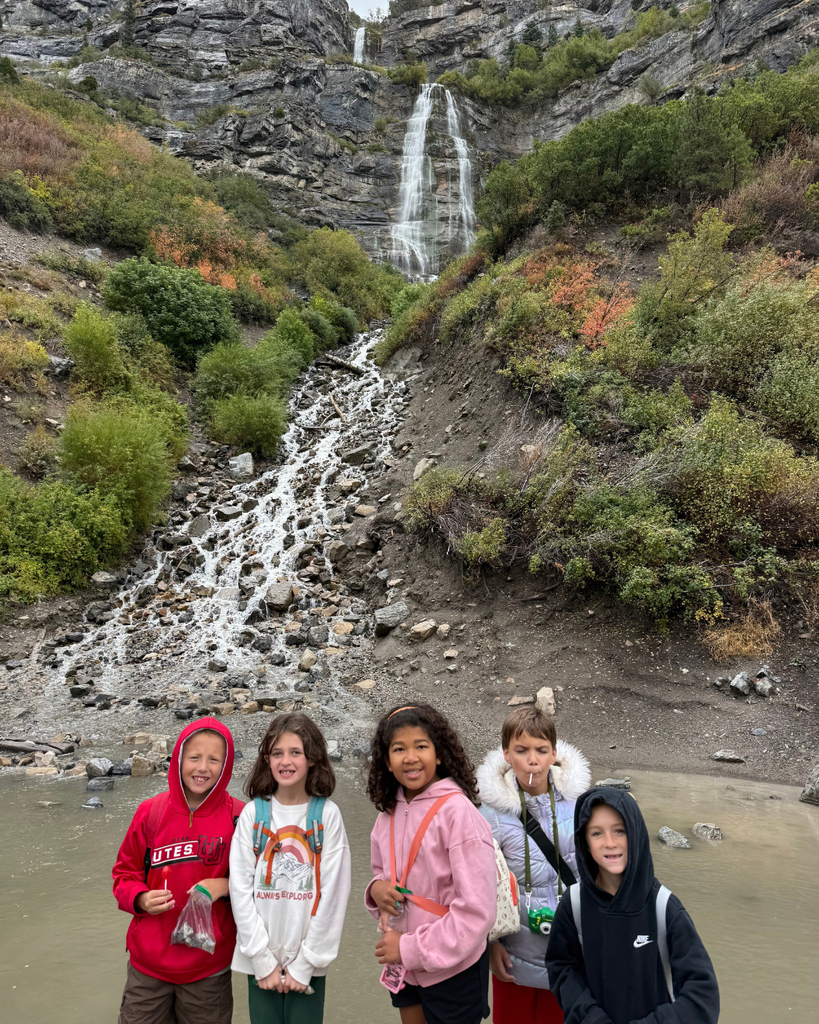 group of students posing in front of the waterfall 