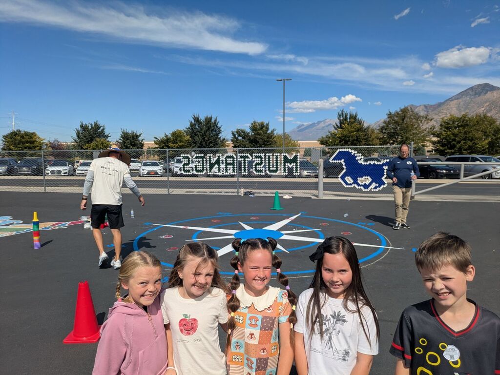 students smiling in front of a newly painted game on the blacktop