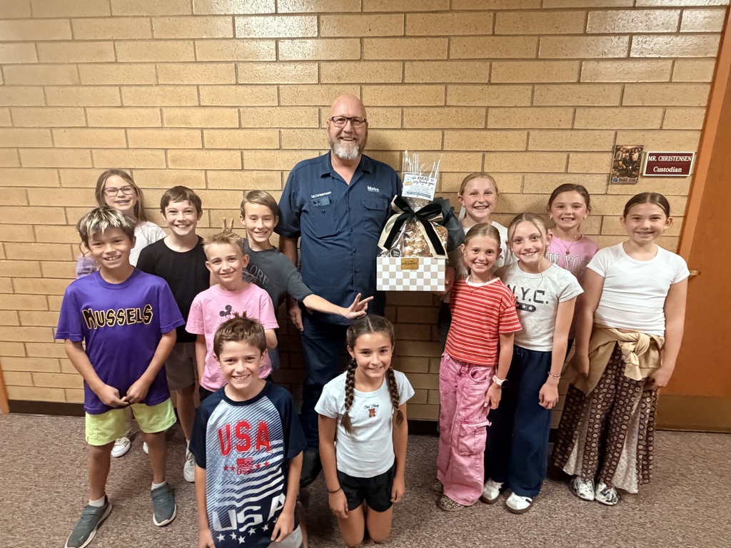 Mr. Christensen holding a gift basket while surrounded by Foothills students celebrating Custodian Day.