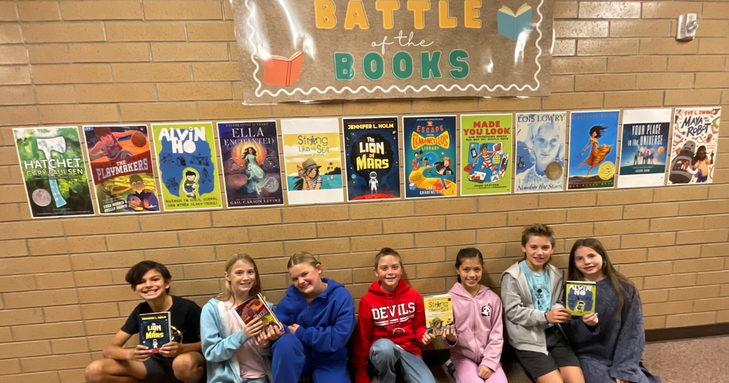 photo of fifth graders posing with books in front of book posters