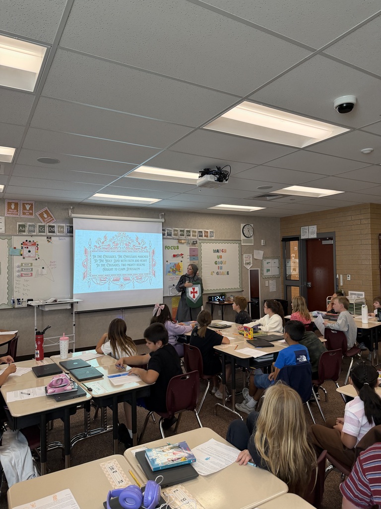students sitting in class listening to a teacher dressed as a knight 