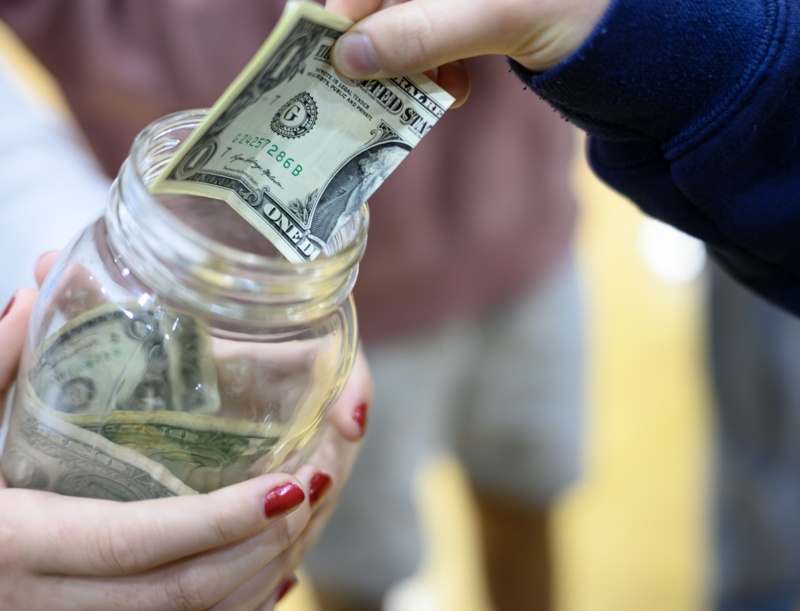 Student putting money in the make a wish jar at the assembly