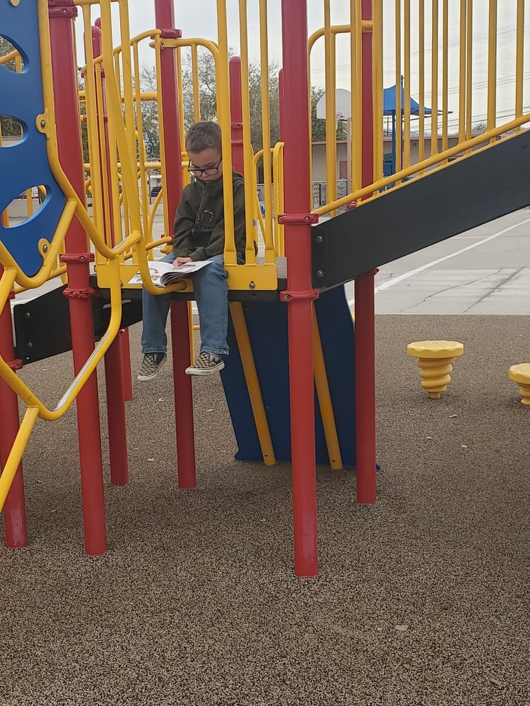 Student reading on jungle gym.