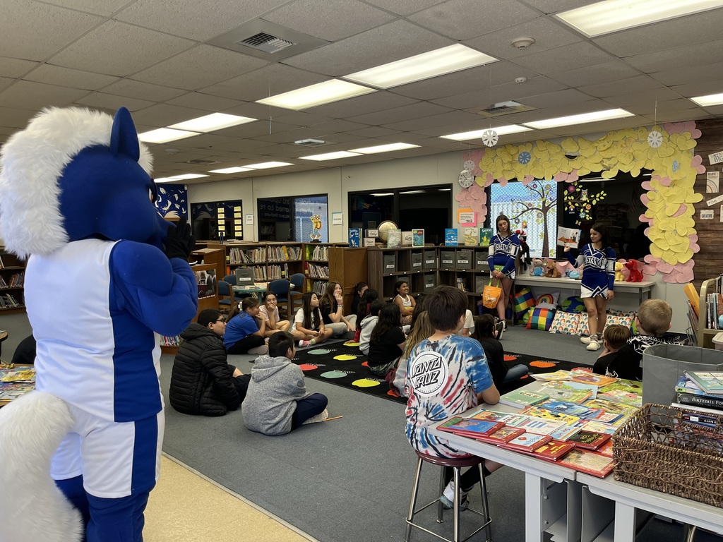 Cheerleaders reading to students.