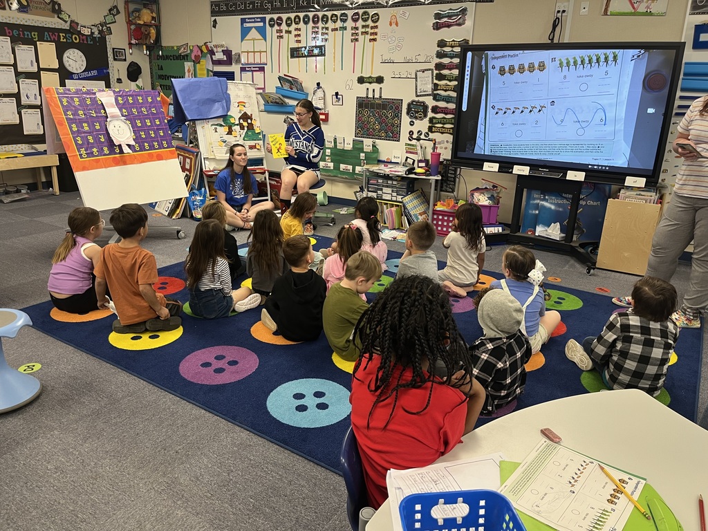 Cheerleaders reading to students.