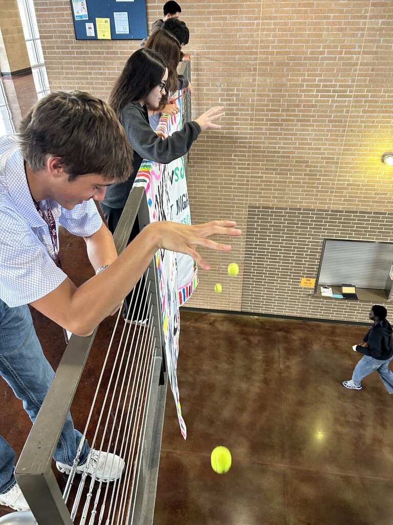 Students bouncing tennis balls off of main stairwell to study acceleration