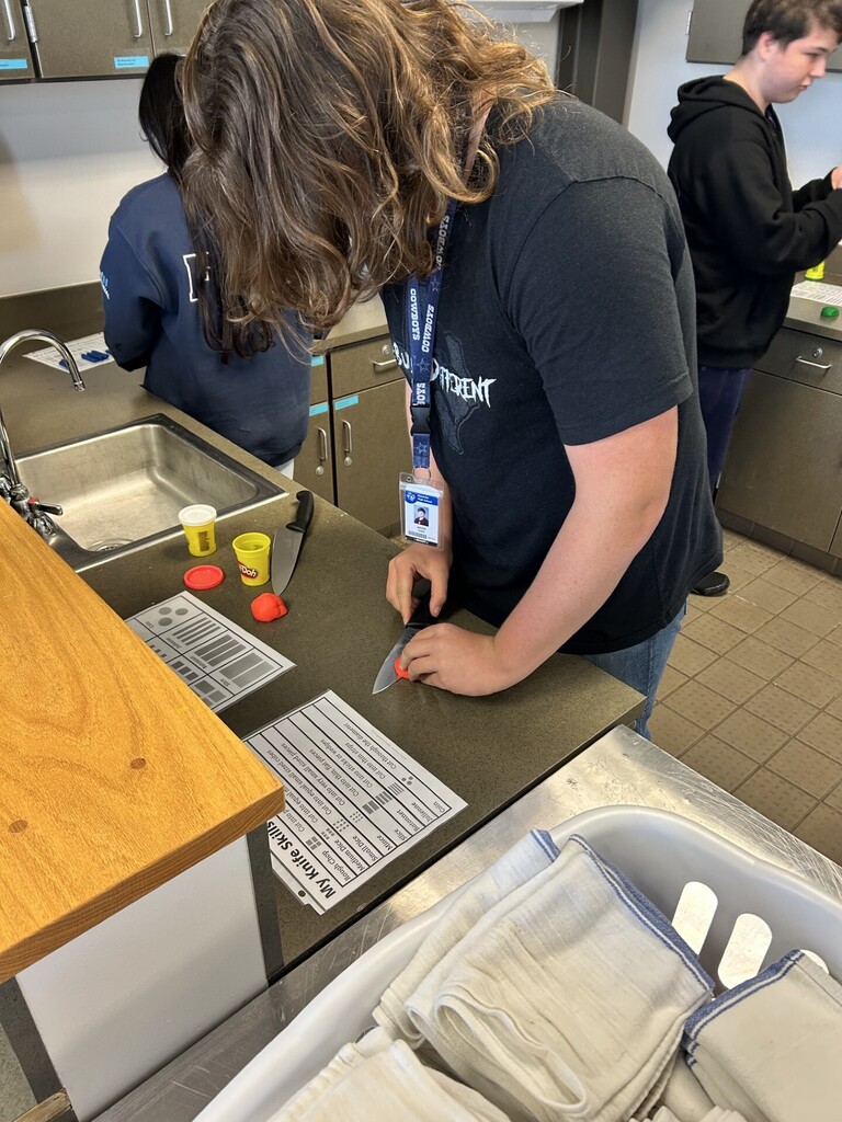 long-haired young man cutting red play-doh