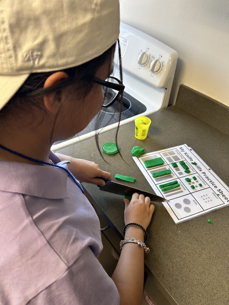 student in backwards cap and glasses cutting green play-doh