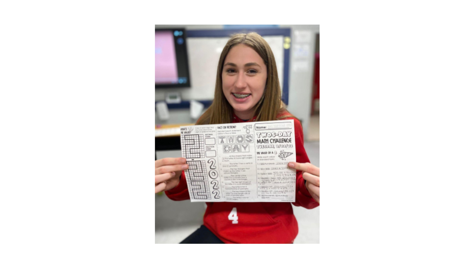 Female student holds up a worksheets about twos day.