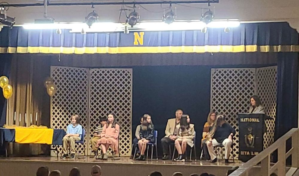 Image of students sitting in chairs on a stage.
