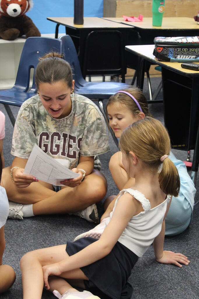girl reading to little girls