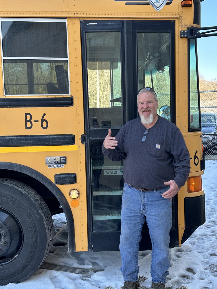Bubba, Bus Driver, standing by his bus in the snow