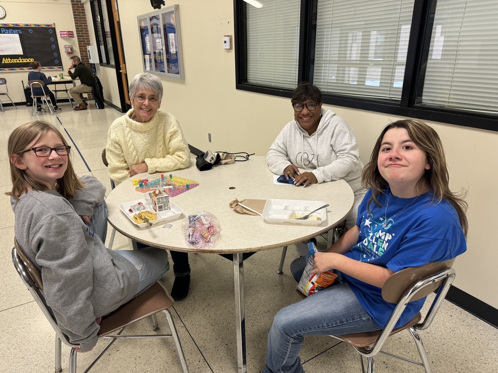 two students sitting at a table with mentors
