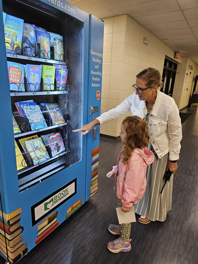 Dr. Eicher showing elementary student the book vending machine. 