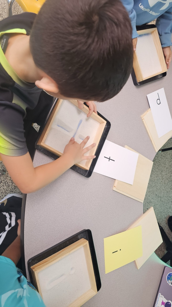 Ms. Junk's Kindergarten intervention students practice letter formation kinesthetically by tracing letters in sand