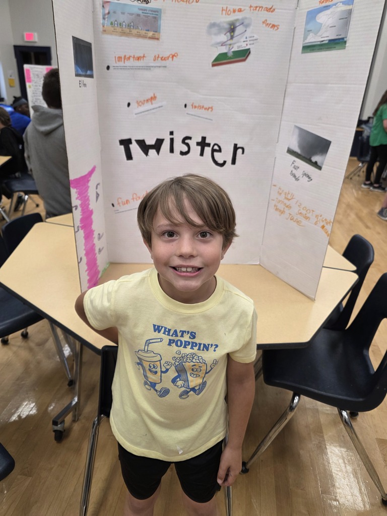 A student standing in front of a twister science fair poster.
