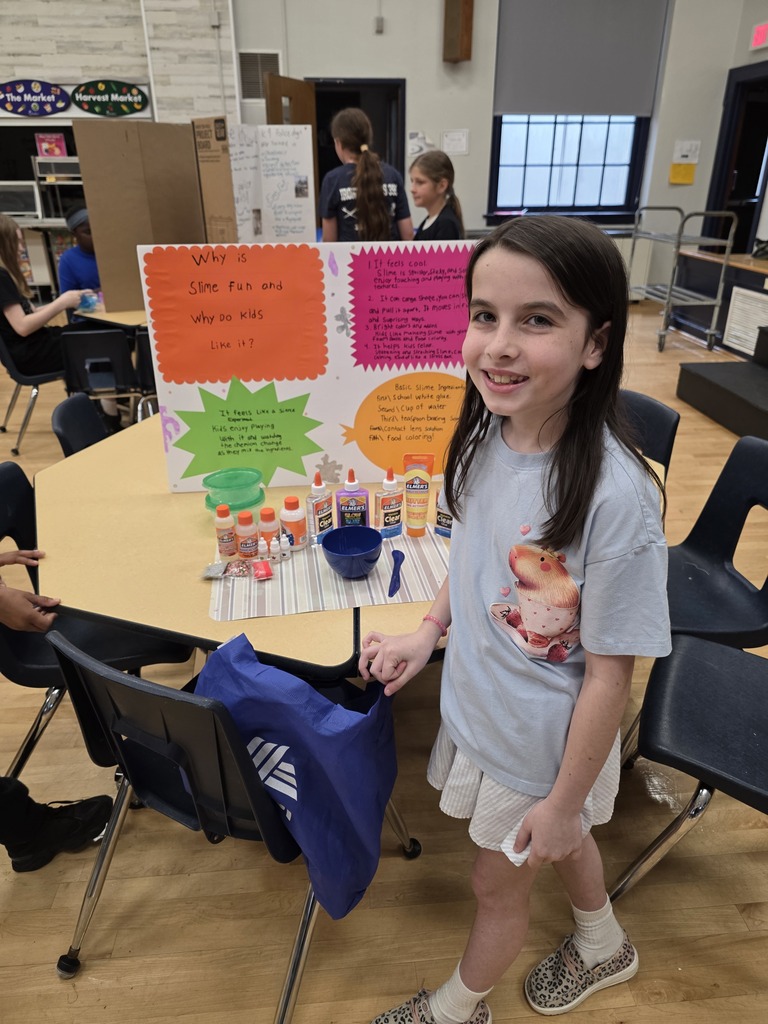 A student standing in front of a slime science fair poster.