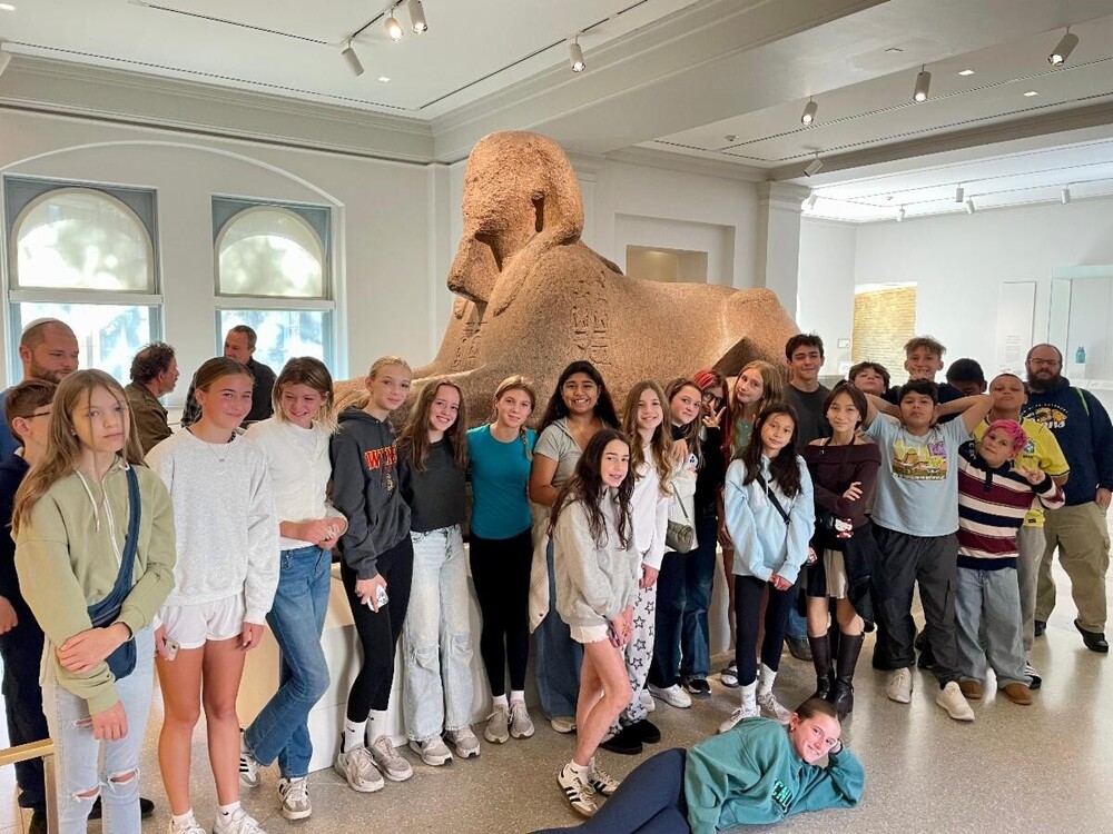 Group of students posing in front of Sphinx model statue at Penn Museum