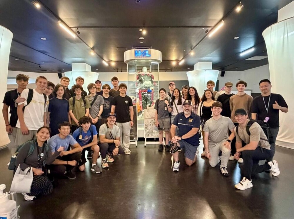 Group of students posing in front of a robot exhibit