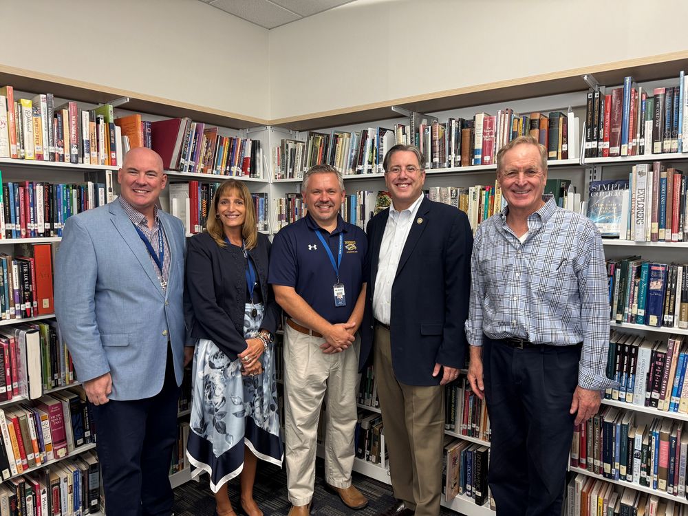Group of 5 people smiling in front of books