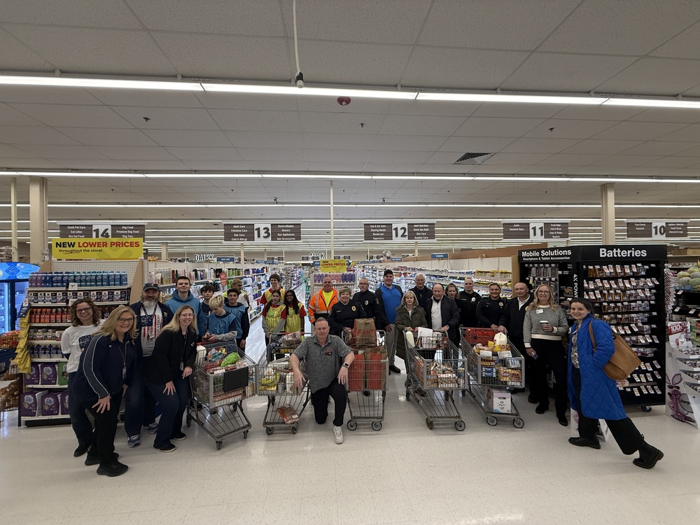 Group of folks standing with 5 full shopping carts in supermarket